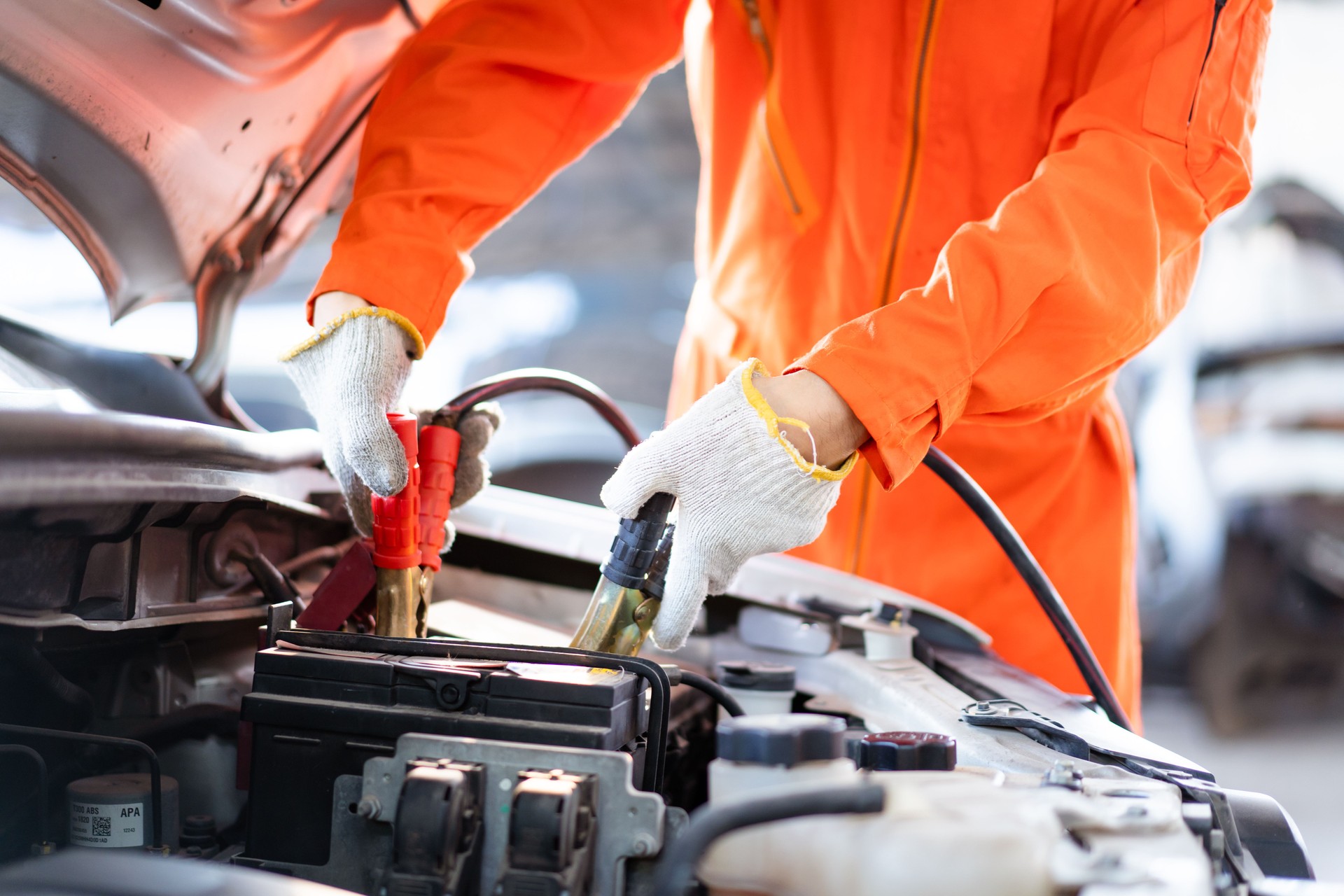 Technician using jump start cable to star an old vehicle.